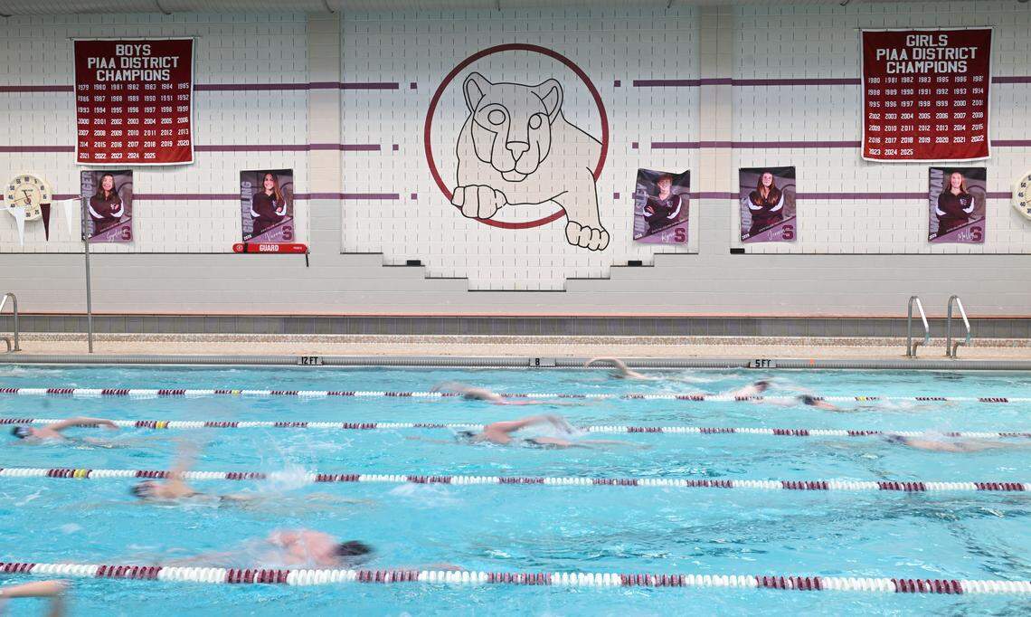 The State College swim team practices on Thursday, March 5, 2026. Banners hang on the wall listing all the district championships. 