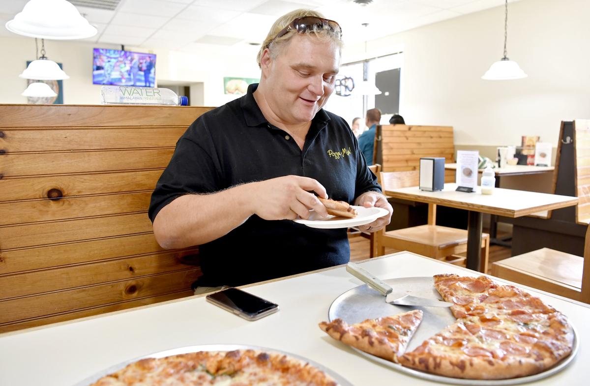 Pizza Mia co-owner John Jennings eats a slice of “hemperoni” pizza on Wednesday. Pizza Mia is hoping to add the product to its menu in the upcoming weeks.