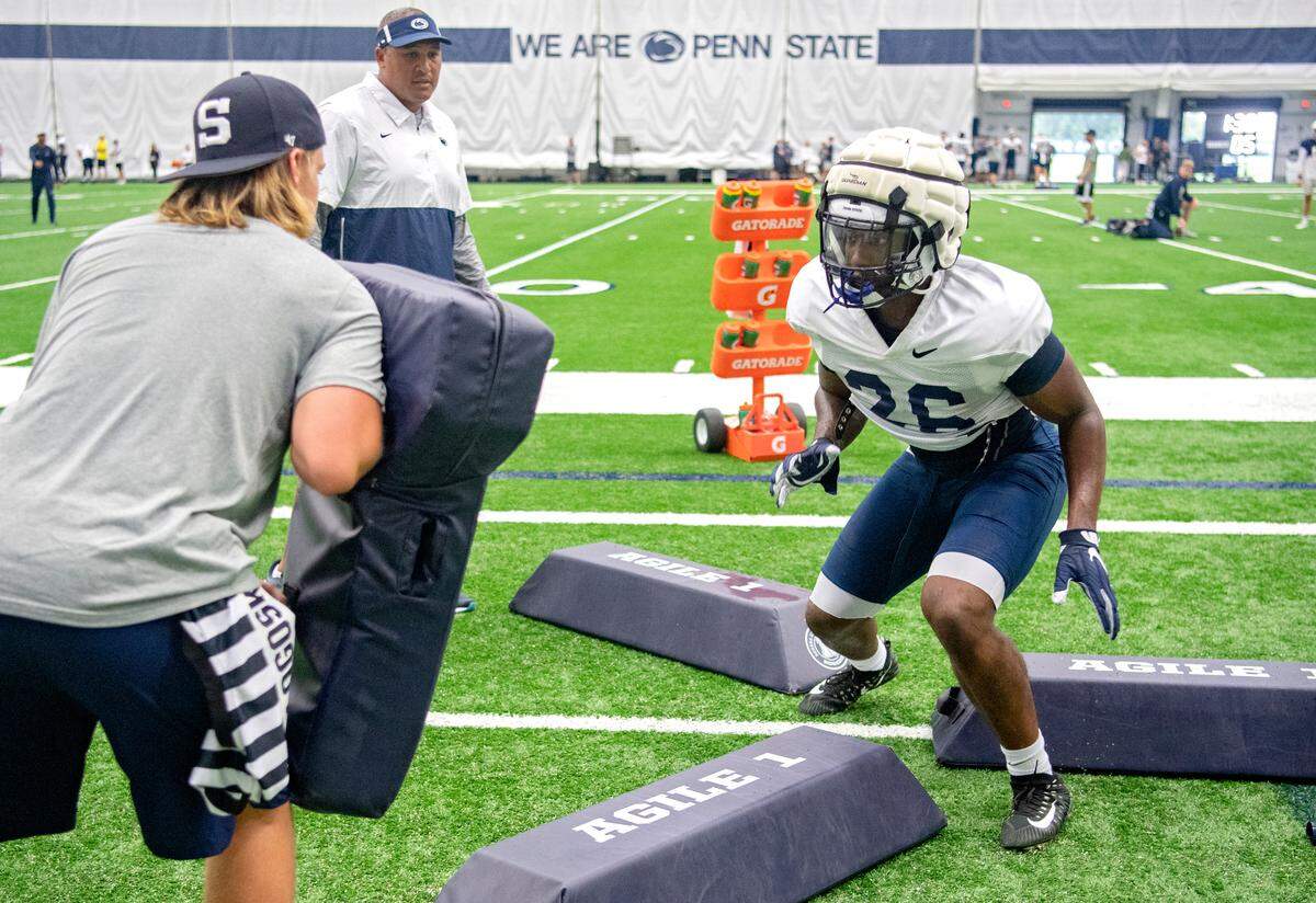 Penn State running back Caziah Holmes runs a drill as coach running backs coach Ja’Juan Seider watches during practice on Wednesday, Aug. 18, 2021.