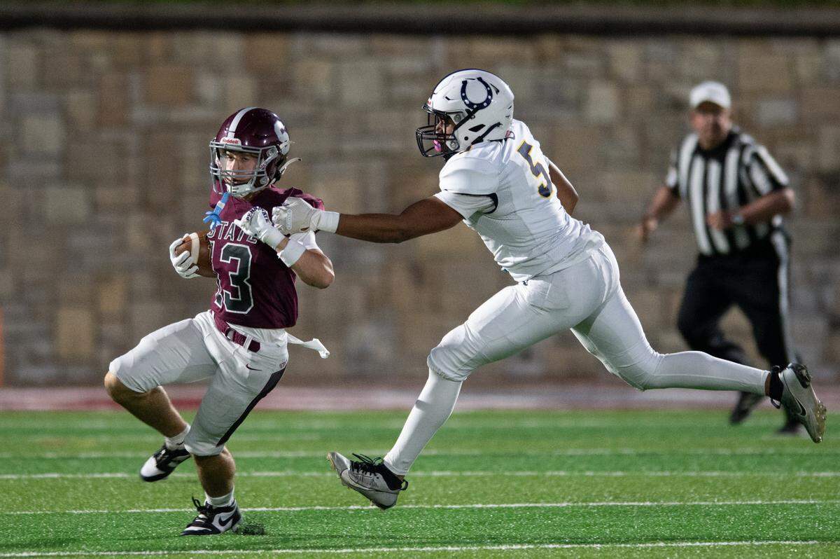 State High wide receiver Hank Lustig, left, breaks a tackle from Cedar Cliff defensive end Jaden Moseley, right, during the football game at Memorial Field on Friday, Oct. 4, 2024.