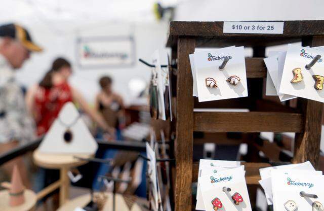 Guests browse the wooden earrings and pins hand painted by Amanda Jones in her Teaberry Design Co. booth at the People’s Choice Festival on Friday, July 14, 2023.