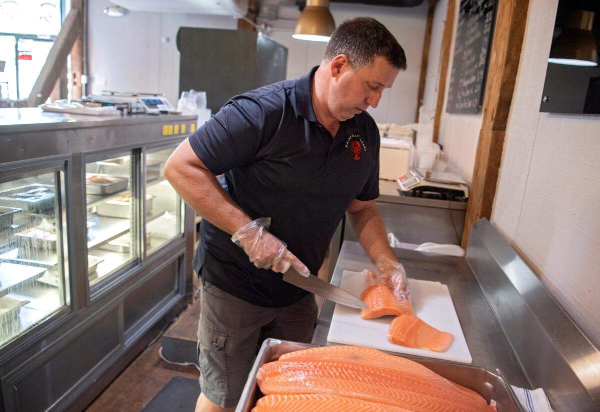 Shaun Knight slices salmon Tuesday for a customer at Maine Bay & Berry.