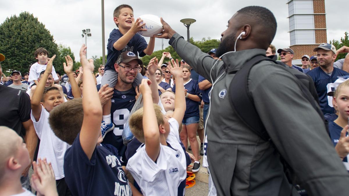 Penn State safety Nick Scott hands a signed football to Jackson Labar, 7, as the Penn State football team arrives for the season opener against Appalachian State at Beaver Stadium on Saturday, September 1, 2018.