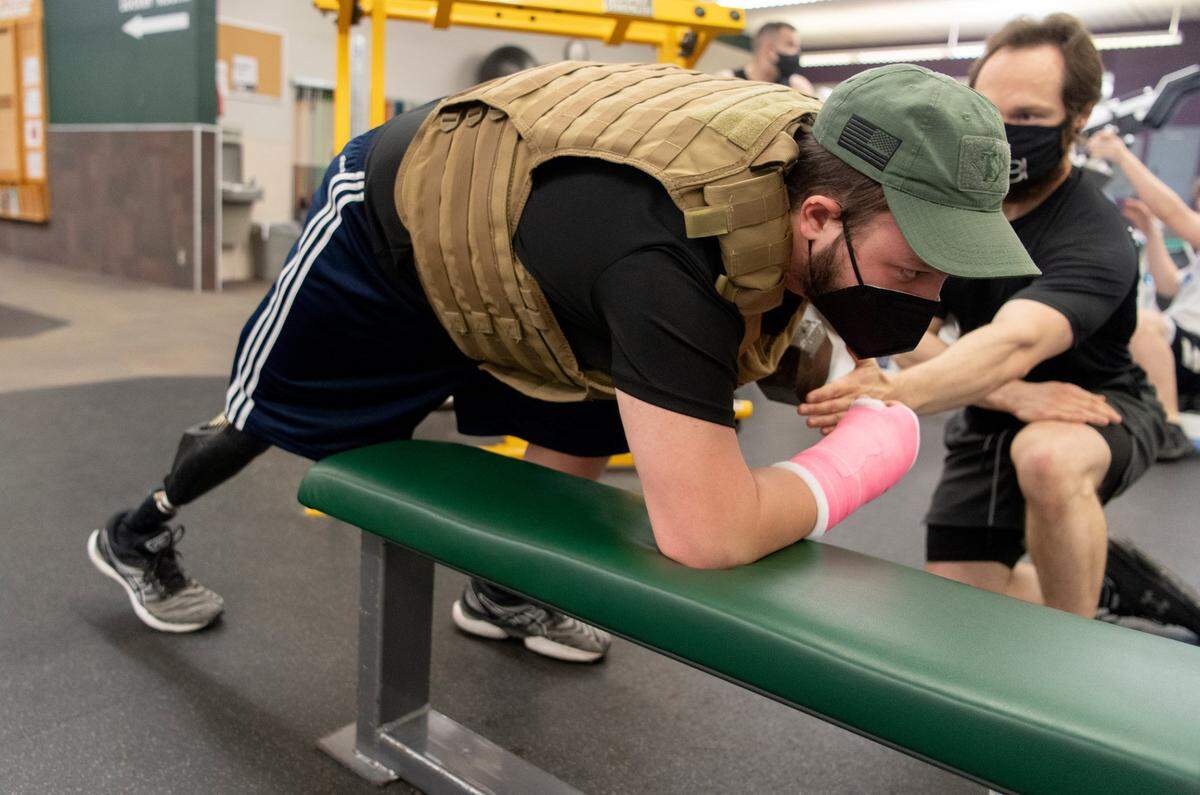 Max Norris from MBI Fitness works with RJ Shirey on exercises at East Coast Fitness on April 6, 2021. RJ wears a 40 lb weighted vest through workouts.