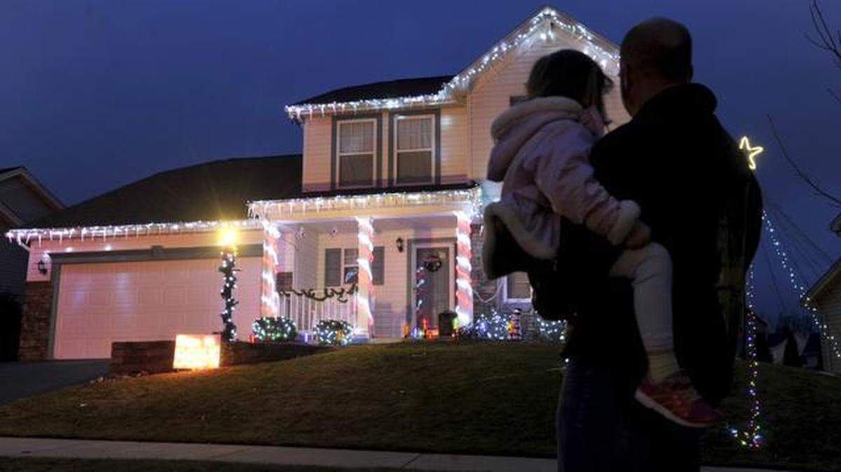 Eric Stoner looks at his Christmas light display that is synchronized to music with his daughter Elizabeth, 6, on Monday, Dec. 8, 2014.
