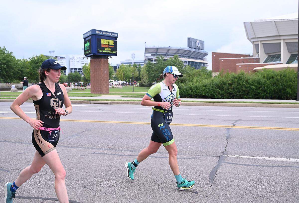 Participants in the Ironman 70.3 Pennsylvania Happy Valley in State College run past the Beaver Stadium and the Bryce Jordan Center on the University Park campus Sunday, June 2, 2023.