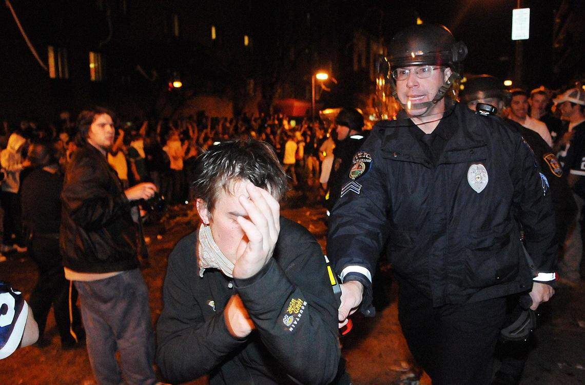 A State College police officer escorts a rioter to the sidewalk during a riot on Beaver Avenue after Penn State’s victory over Ohio State in October 2008