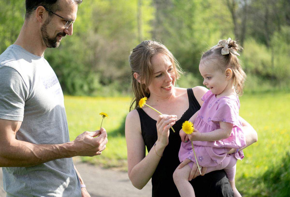Freya Barragan laughs with her parents Adrain and Carly as they pick dandelions and flowers on Tuesday, April 30, 2024. The family is hoping to get a service dog for Freya to help with her seizures caused by Dravet syndrome.