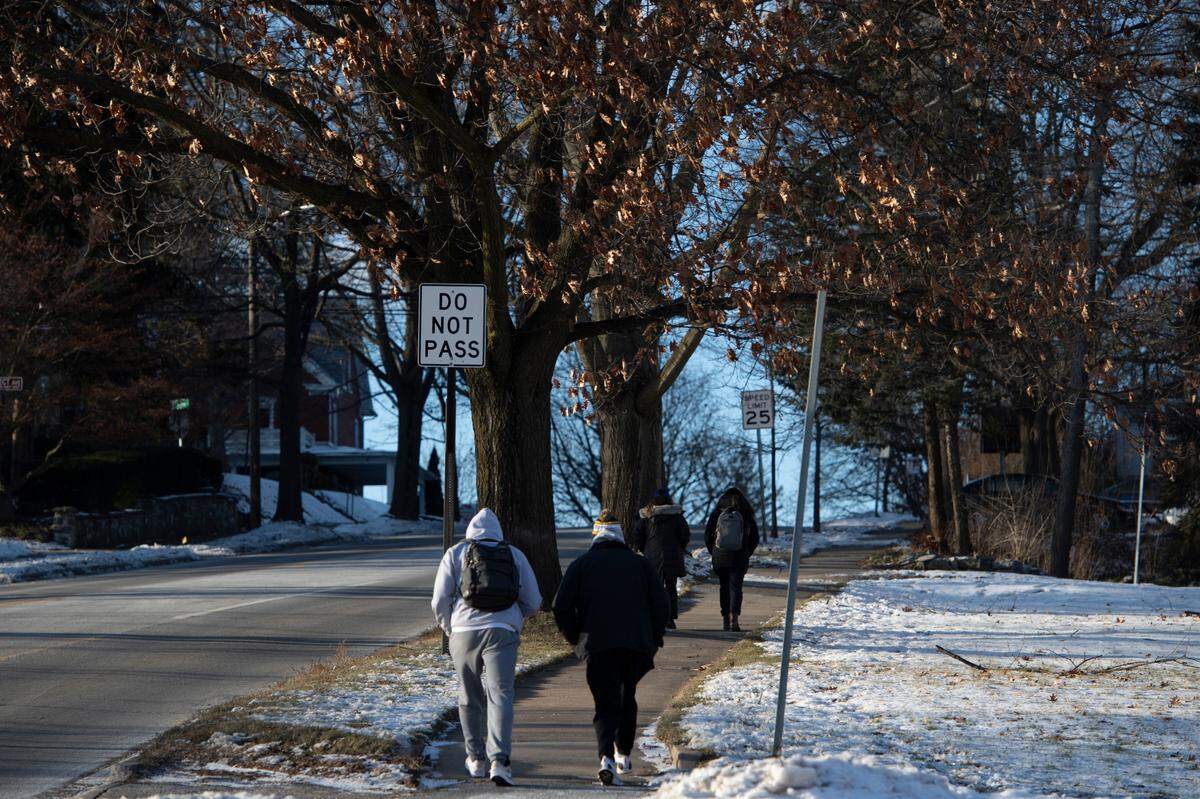 People walk past trees along South Atherton on Tuesday in State College. About 60 trees along a stretch of the street between Westerly Parkway and Curtin Road could be removed as part of an upcoming roadway project.