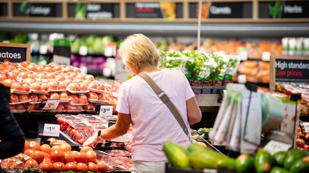 A woman browses produce at a grocery store.