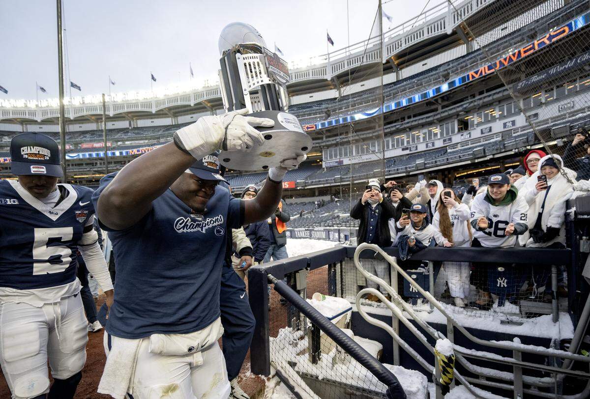 Penn State offensive lineman Anthony Donkoh holds up the Pinstripe Bowl trophy to cheering fans after the win over Clemson at Yankee Stadium on Saturday, Dec. 27, 2025.