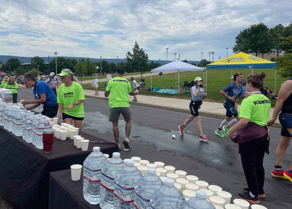 Runners pass by a hydration station Sunday, June 14, 2026, at the Ironman 70.3 Pennsylvania Happy Valley North American Championship in Centre and Clinton counties.
