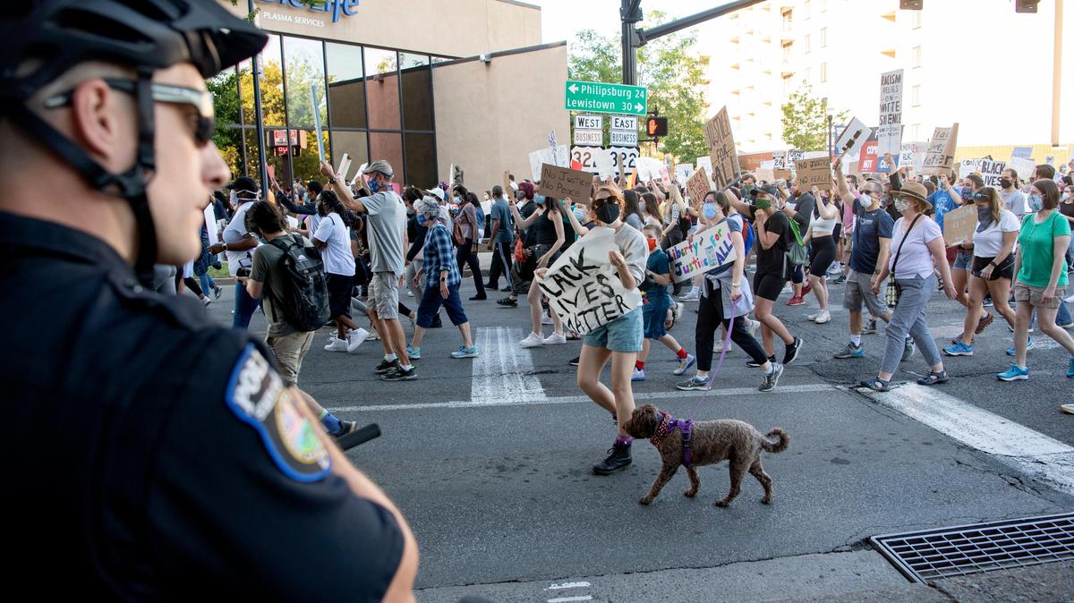 A police officer watches as hundreds of people march up Atherton Street during a “Justice for Black Lives” protest in June 2020. After more than a year of discussions and planning, the State College Borough Council approved an oversight board Monday aimed at increasing accountability in the local police department.