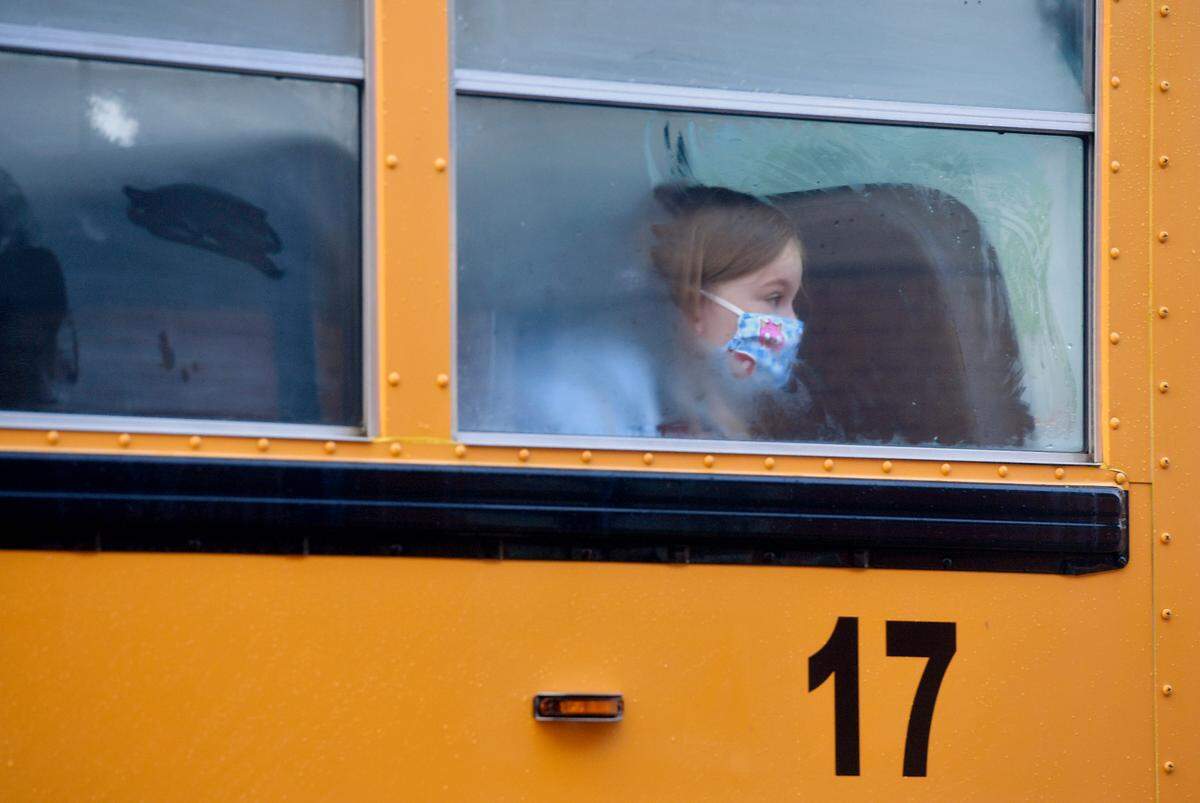 A student wearing a mask looks out the foggy window as the bus pulls up at Wingate Elementary for the first day on Tuesday, Aug. 25, 2020.