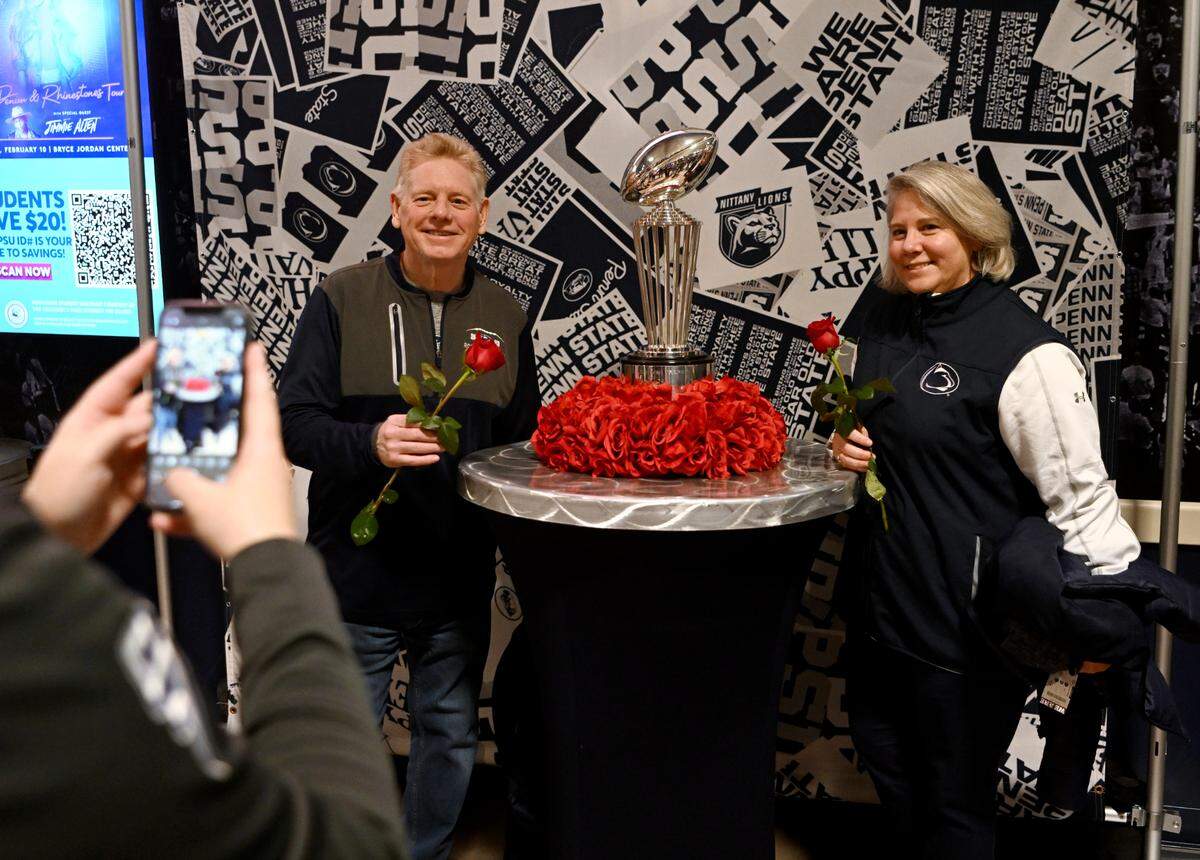 Penn State fans get their picture taken with the Rose Bowl Trophy before the Penn State wrestling match on Friday, Jan. 27, 2023 at the Bryce Jordan Center.