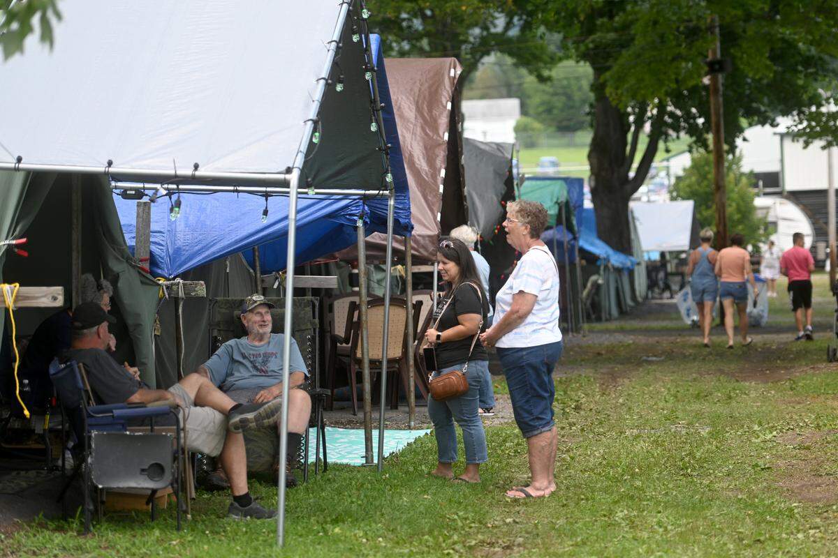 Friends stop to chat the tents at the Centre County Grange Encampment and Fair on Friday, Aug. 18, 2023.  