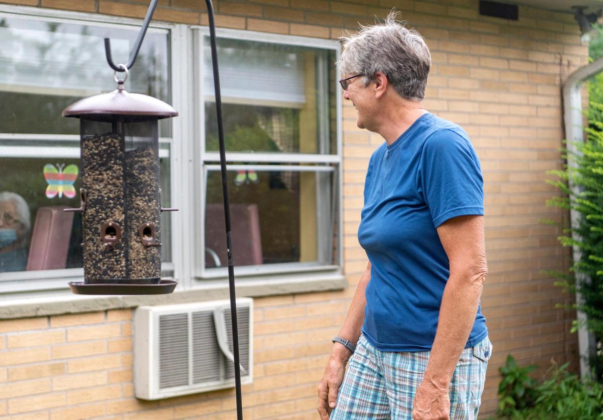 Cindy Way interacts with residents AristaCare at Hearthside through the windows Friday as she fills a bird feeder.