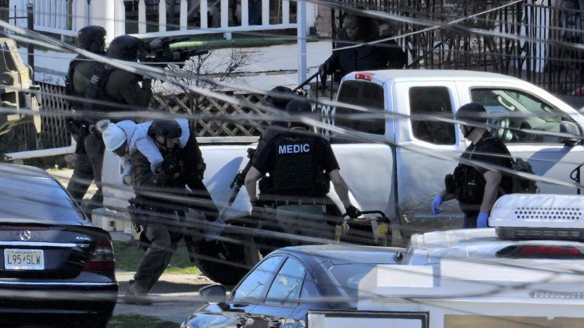 A resident is evacuated from a home in Trenton, N.J. on Saturday, March 16, 2024. A suspect has barricaded himself in the home after allegedly shooting three people to death in suburban Philadelphia on Saturday, authorities said. The Trenton Police Department said the suspect is believed to be hiding in the house and that the residents were successfully evacuated with no injuries.