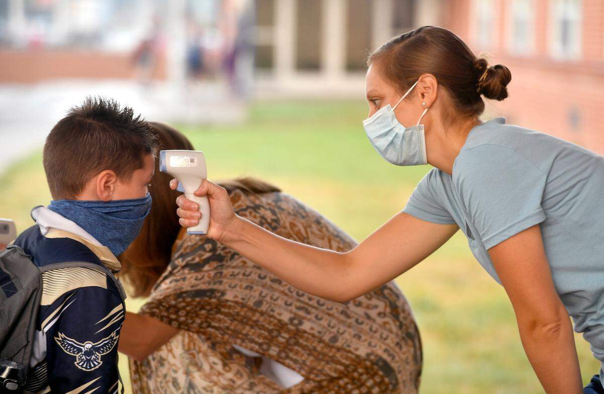 Wingate Elementary nurse Lauryn Bostdorf checks the temperatures of students as they arrive for the first day of school on Tuesday, Aug. 25, 2020.