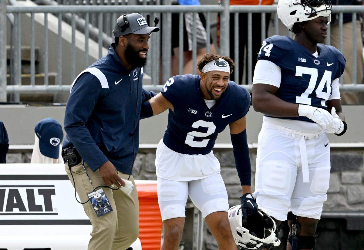 Penn State defensive line coach Deion Barnes and safety Keaton Ellis laugh together on the sidelines during the Penn State Blue-White game on Saturday, April 15, 2023.