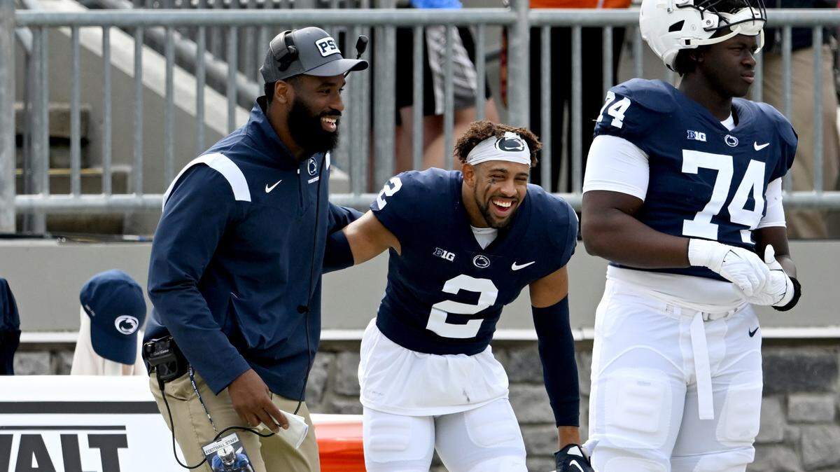 Penn State defensive line coach Deion Barnes and safety Keaton Ellis laugh together on the sidelines during the Penn State Blue-White game on Saturday, April 15, 2023.