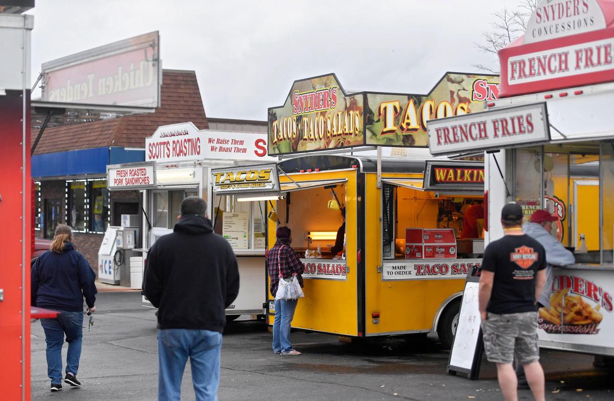 Patrons stand apart from each other and wear masks as they order food from Scott’s Roasting and Snyder’s Concessions in the parking lot of the Zion Mart on Friday, April 24, 2020.