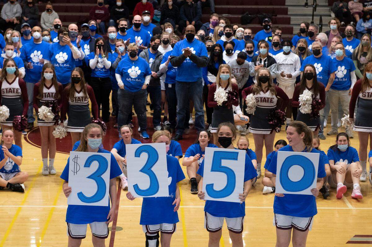 State College Area High School students reveal the amount raised for former boys basketball assistant coach Rudy Burruss during a “Blue Out” game held Tuesday in his honor.