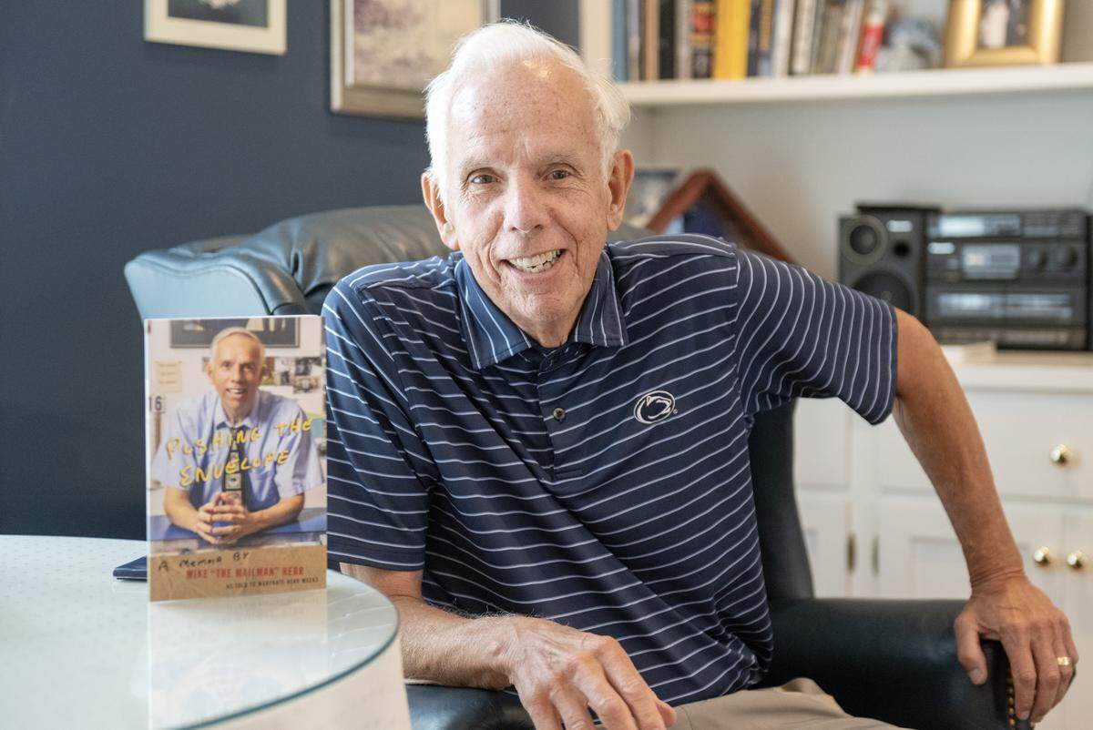 Mike Herr, known as Mike the Mailman, with his memoir “Pushing the Envelope” in his home on Tuesday, Oct. 21, 2025.  