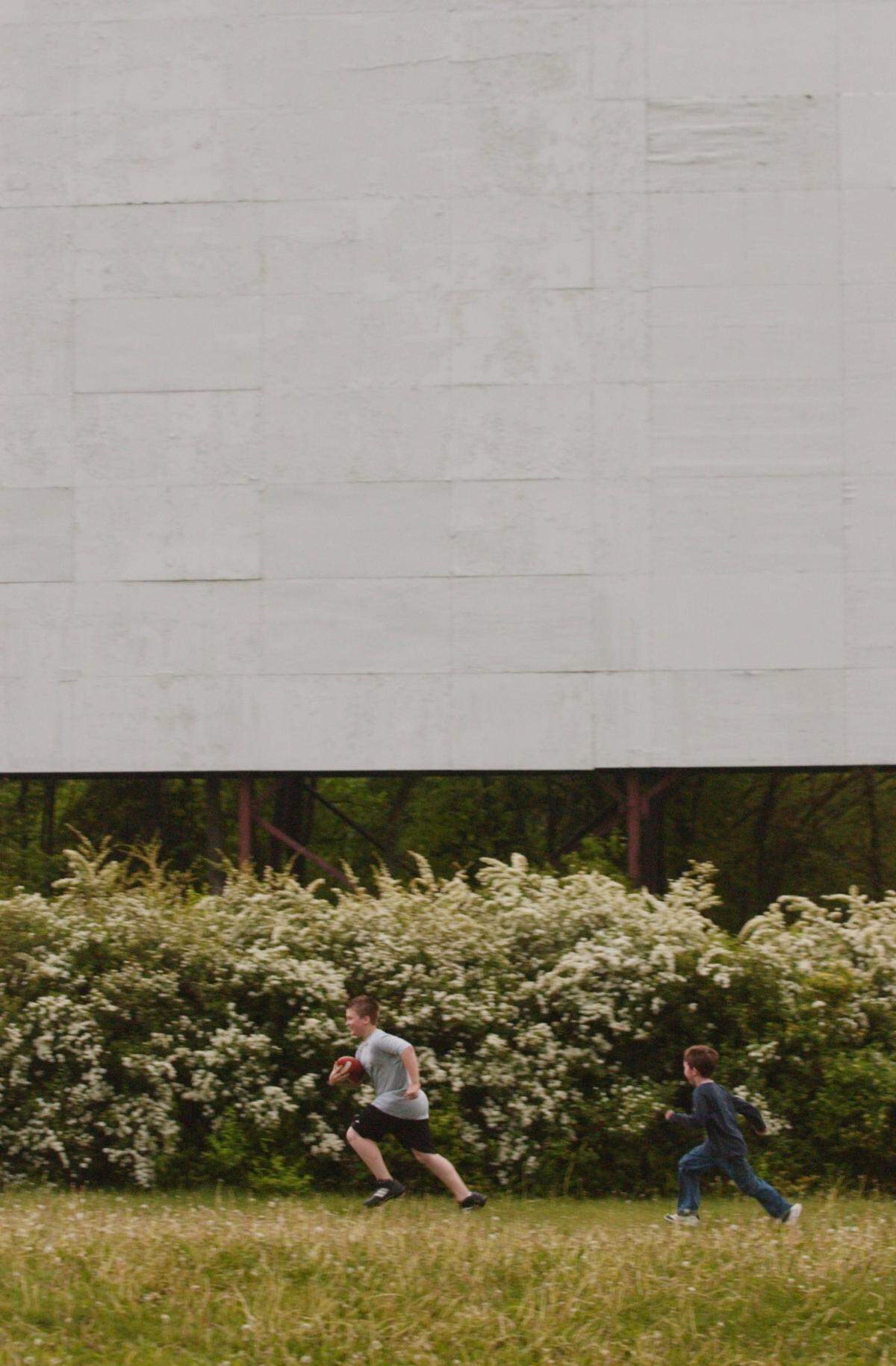 Mike O’Donnell chases Alan Detweiler while playing football while waiting for the movie to begin at the Starlite Drive-In Theatre Saturday night, May 15, 2004.