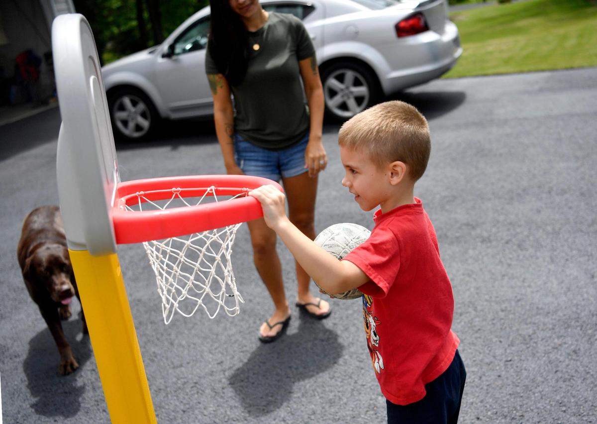 Angelan Mundy cheers on one of her sons, Daxtin, 5, to make a basket in the driveway of the family’s home in Centre Hall on Wednesday.