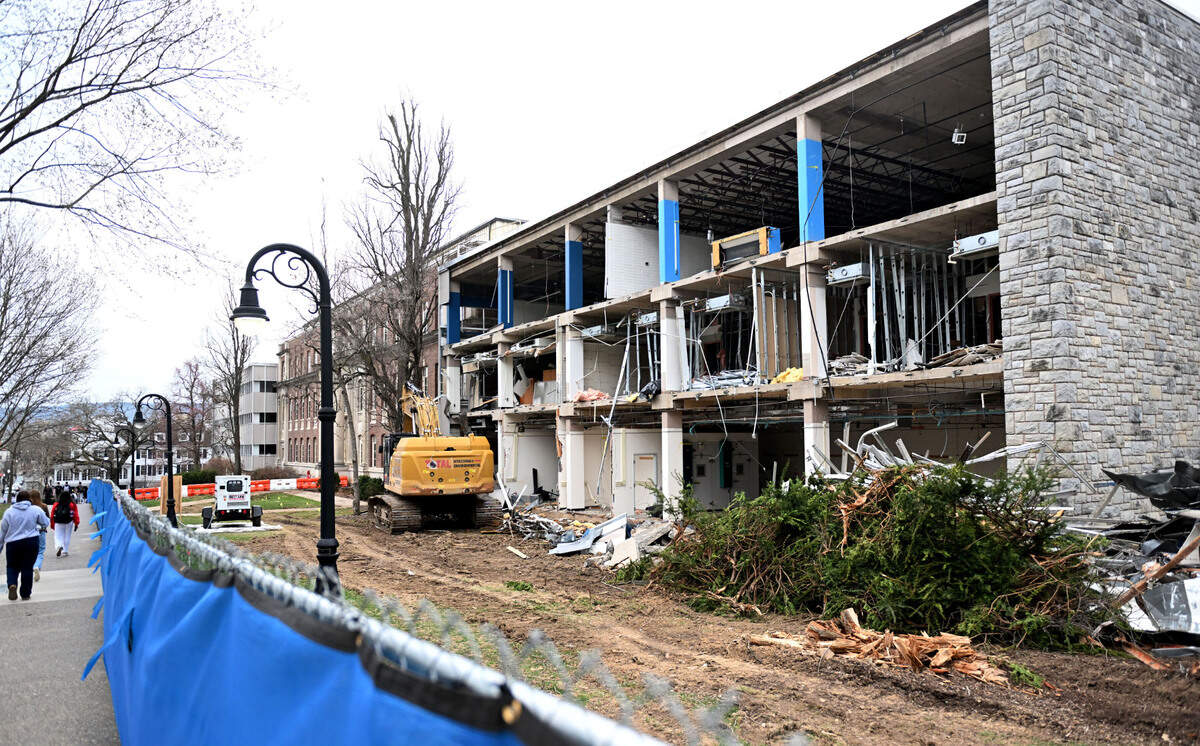 Students walk by portions of the Sackett Building that are being demolished on the Penn State campus on Monday, March 31, 2025.