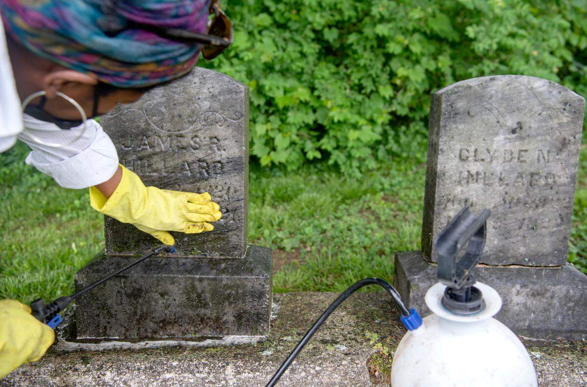 Renea Nichols tries to make out the date of a grave maker as she cleans it at the Union Cemetery in Bellefonte on Thursday.
