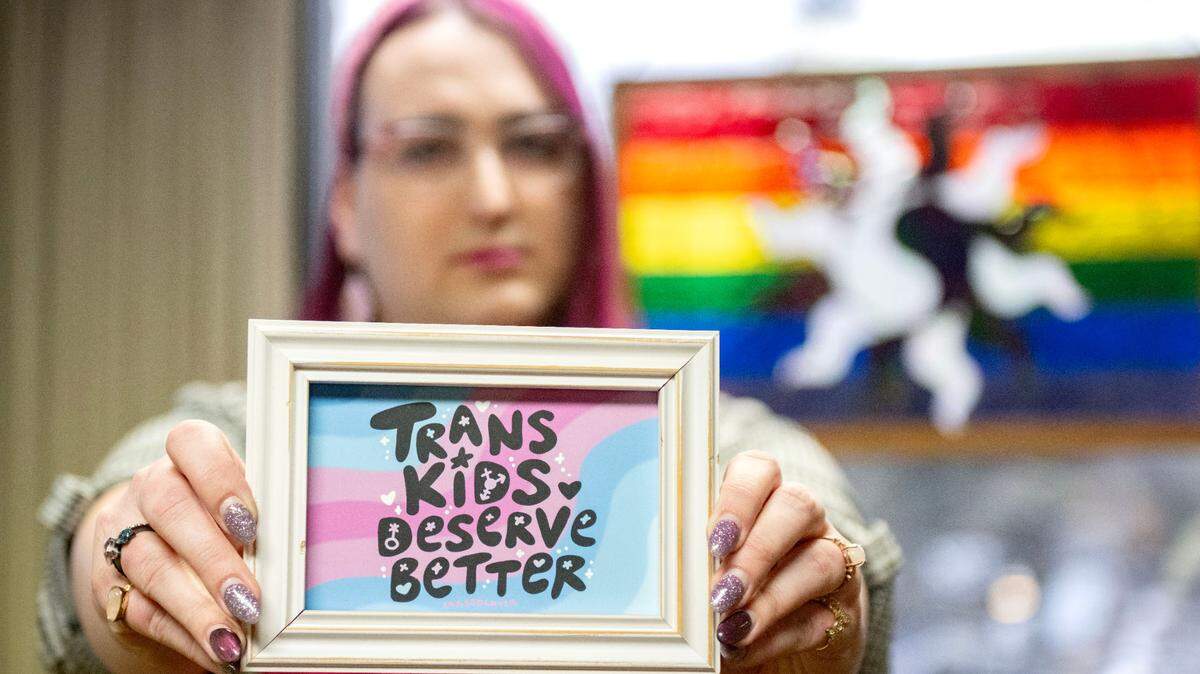 Michel Lee Garrett holds up a piece of artwork that supports trans kids in the lobby of the Centre LGBT+ center on Thursday, Feb. 20, 2025.