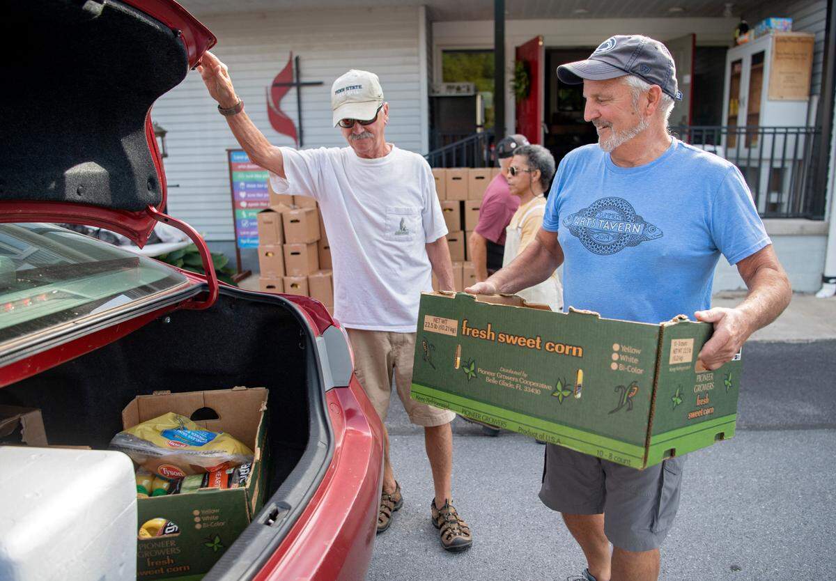 Volunteers including Dave Baughman help to load food into cars as part of the YMCA food distribution at the Howard United Methodist Church on Thursday, July 7, 2022.