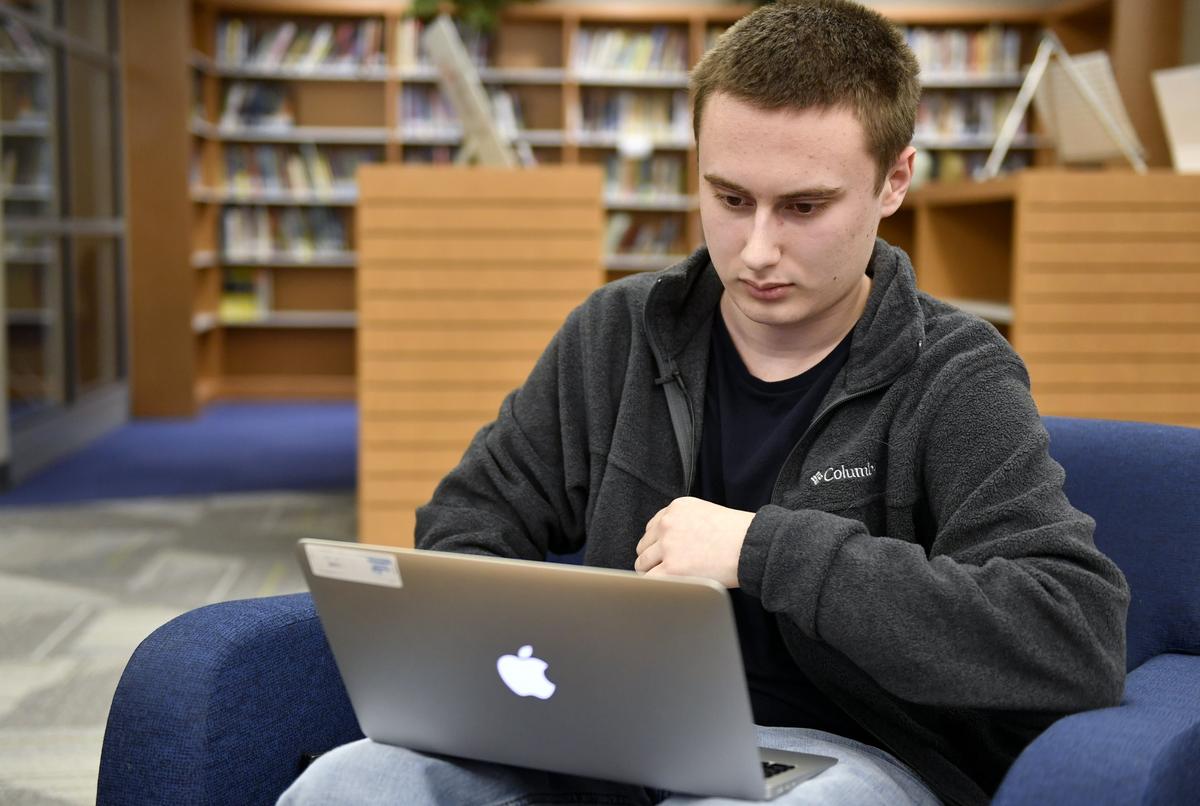 Penns Valley High School senior Ian Dodson pulls up his Google Classroom account from the library of the school on March 25, 2019. Though the school gives every student a laptop, internet connections at home vary for their students.