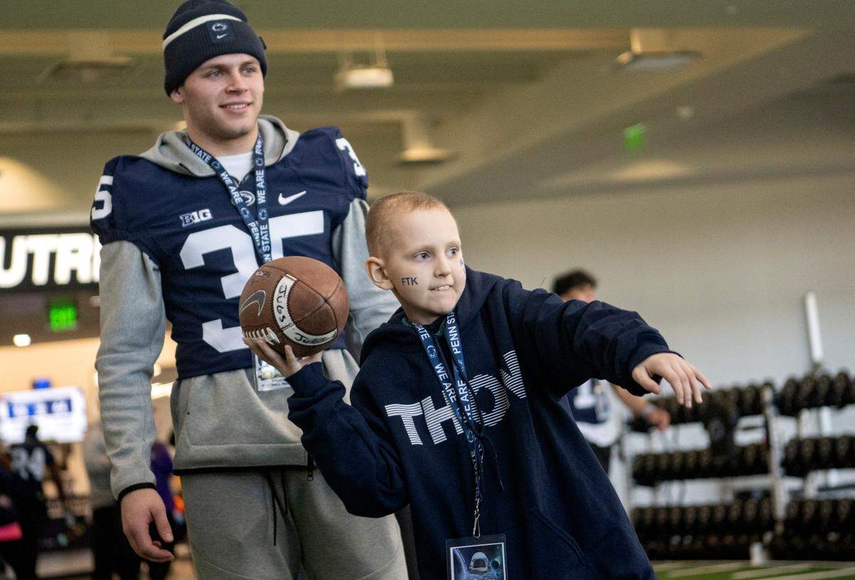 Riley Rejniak, 10, plays catch with his brother as Penn State cornerback Jace Tutty smiles during the Thon Explorers program at the Lasch Building on Saturday, Feb. 18, 2023.