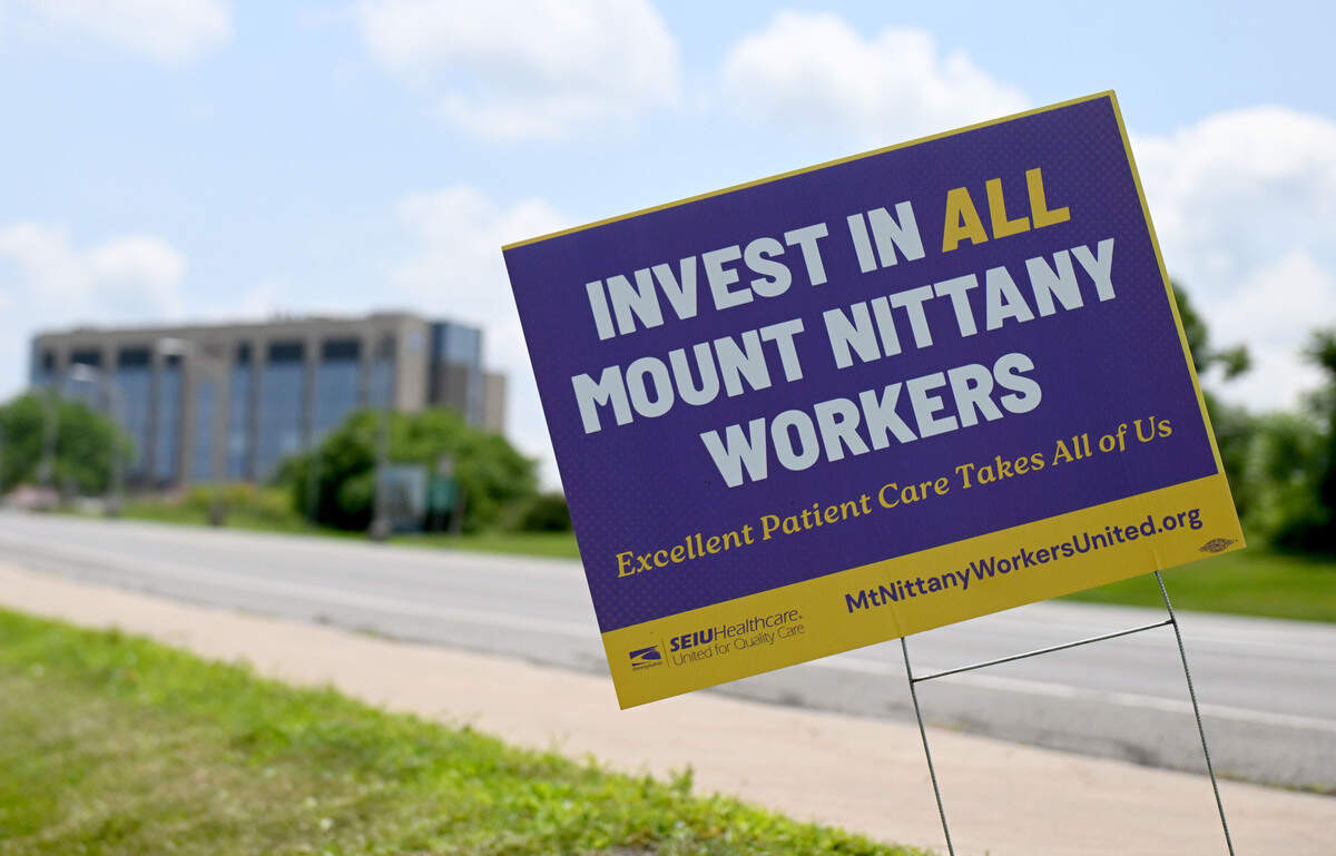 A sign to invest in all Mount Nittany workers along Hospital Drive with Mount Nittany Health’s new patient tower in the background on June 30, 2026.