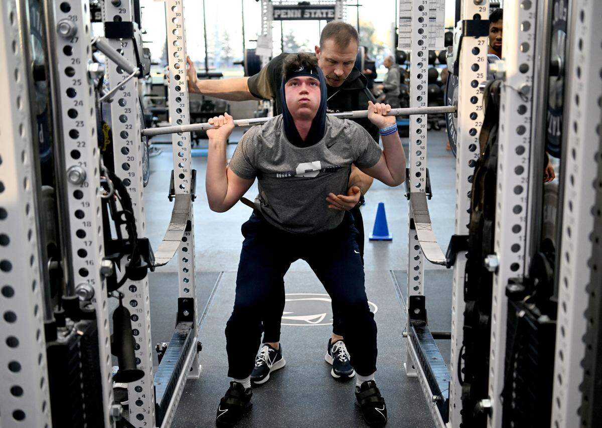 Penn State strength and conditioning coach Chuck Losey spots for quarterback Drew Allar as he lifts during a winter workout session on Thursday, Feb. 29, 2024.