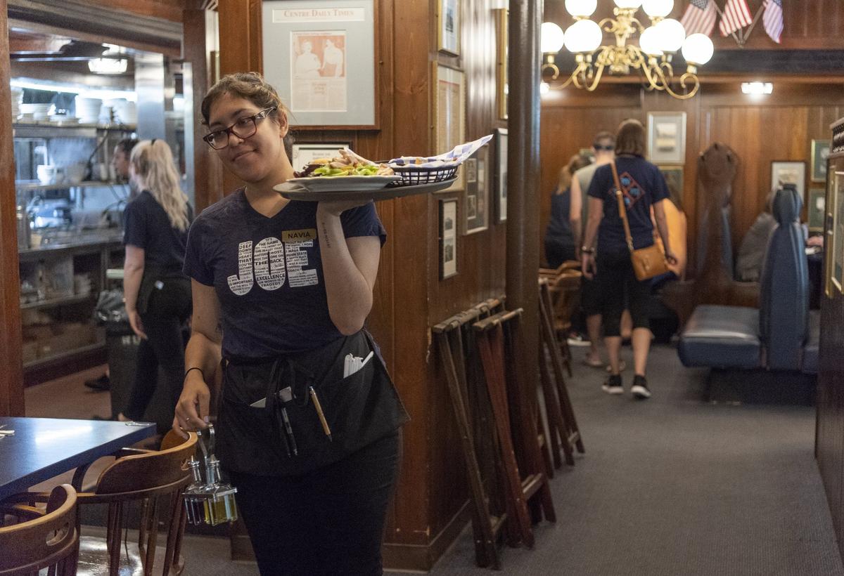 Waitress Navia Prezeau takes a tray of food to a table at The Corner Room on June 7.
