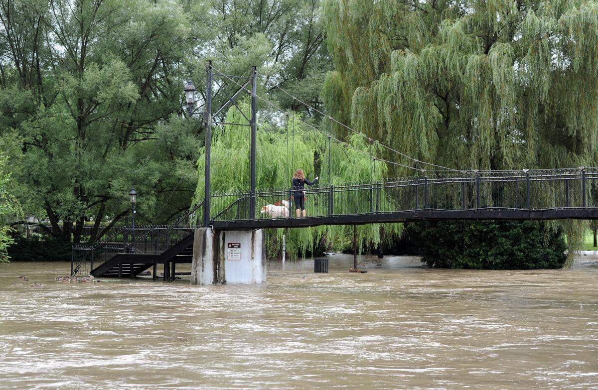 Diana Dombrowski and her dog view the flooded exit off of the bridge over Spring Creek in Talleyrand Park Friday, Aug 3, 2018 in Bellefonte.