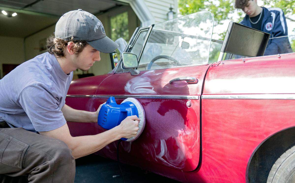 Dylan Beck polishes the door of his 1974 MGB as he and his friends work to restore the car on Thursday, May 15, 2025.