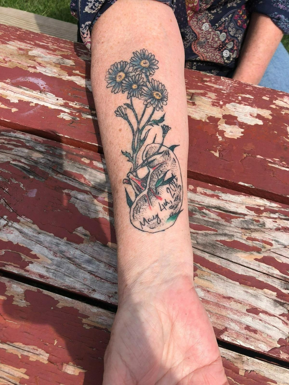Maureen Stathes, 60, shows off her new tattoo from Ikonic Tattoo (123 S. Allen St.) over a picnic table at Talleyrand Park in Bellefonte. The tattoo represents her kidney donation to a stranger. “The kidney has new sprouts of life in it and then grows up into daisies, which are my favorite flowers,” Stathes explained.