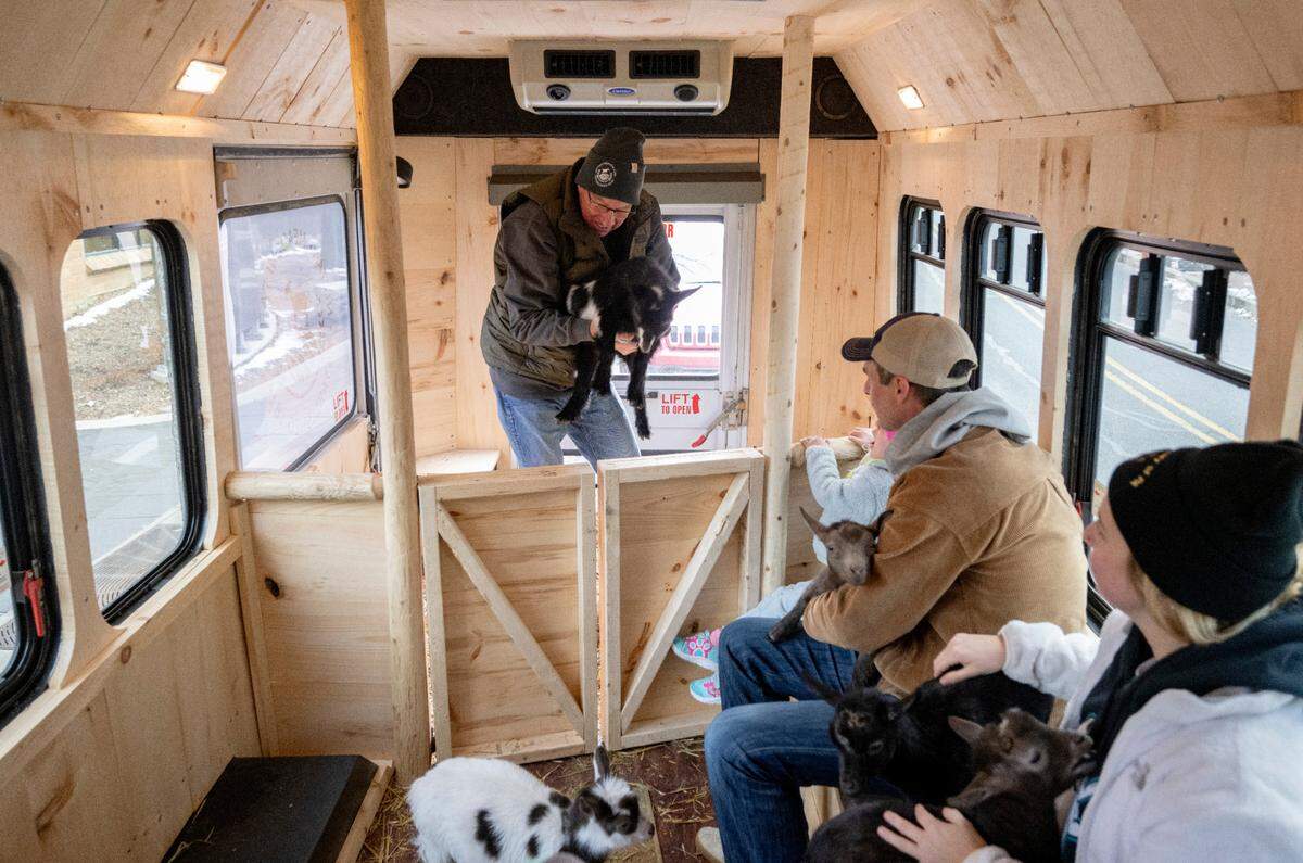 Nittany Meadow Farm’s Mike Immel hands a goat to visitors in Goats2Go on Friday. Goats2Go, the farm’s new mini-bus to bring baby goats to you, held a ribbon cutting in downtown State College.