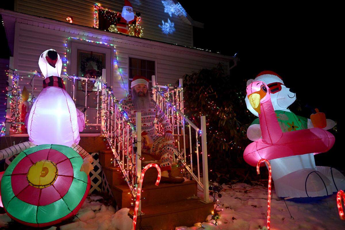 Fran Gray, 52, sits on the steps among the bright holiday decorations on his family’s home in Rush Township on Wednesday, Dec. 21, 2022.