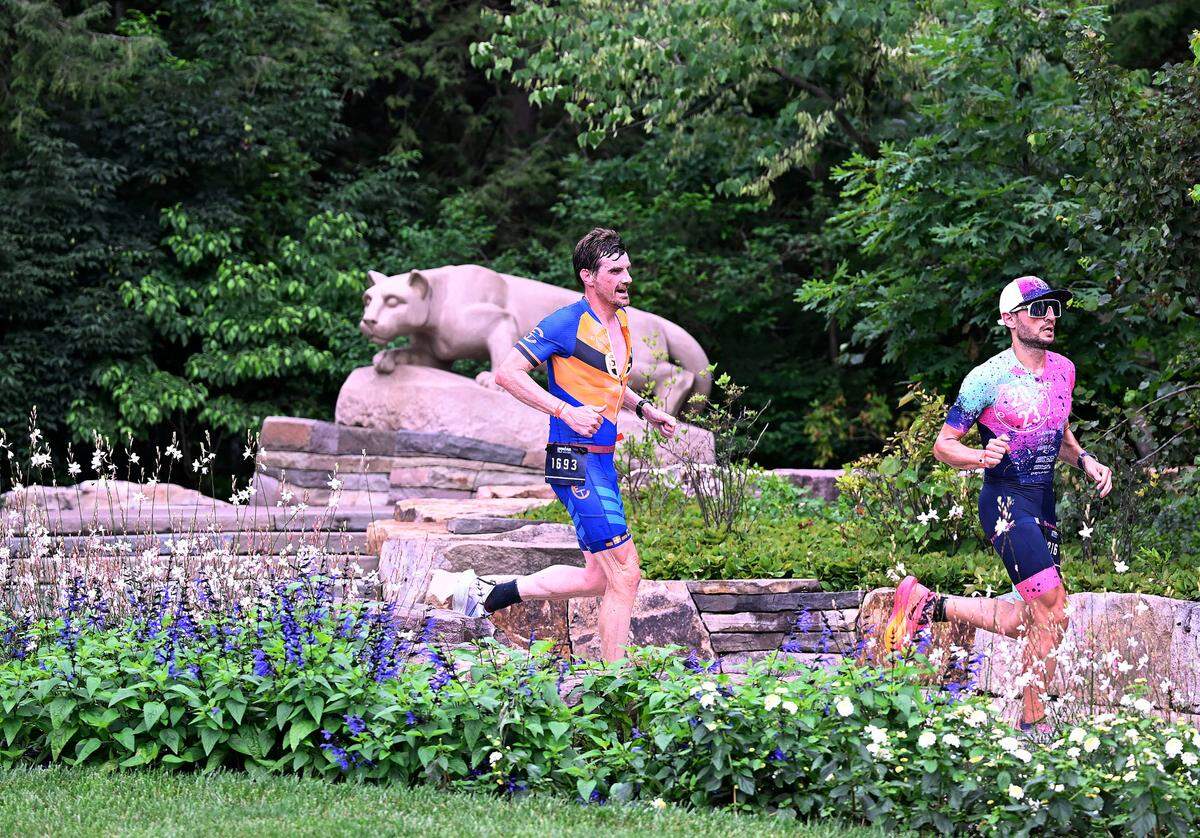 Participants in the Ironman 70.3 Pennsylvania Happy Valley run past the Nittany Lion Shrine on the Penn State campus Sunday, July 2, 2023.