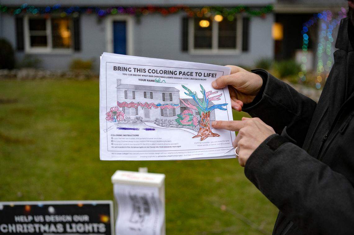 Spud Marshall shows one of the holiday light coloring pages he received, which included a cat face on the tree. His house features the design of a different youngster each night.