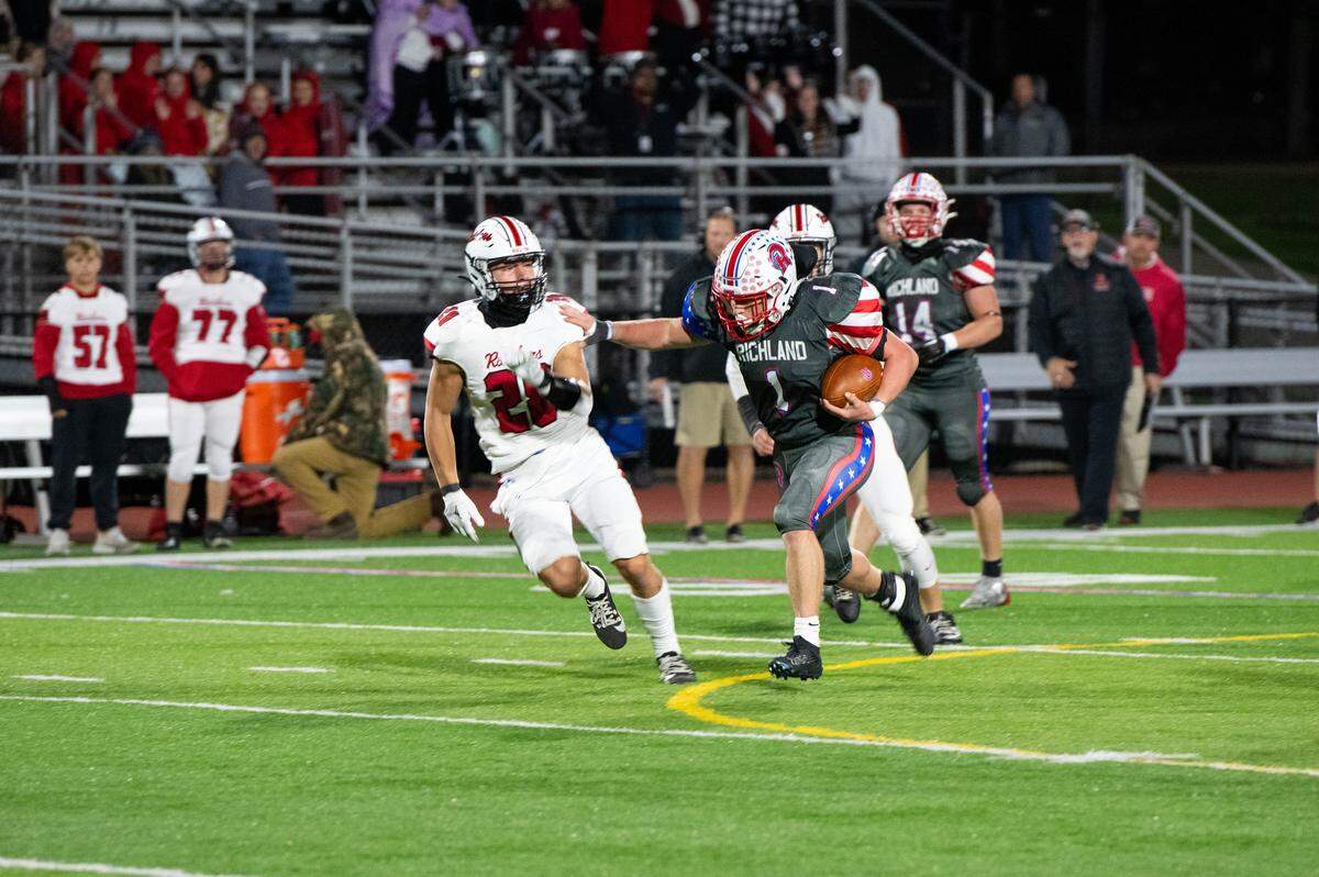 Richland junior Grayson Mahla (1) stiff arms a defender during a Friday night football game against Bellefonte in Johnstown, Pa., on Oct. 10, 2025. The Rams beat the Red Raiders 33-29.