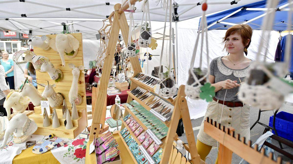 Molly Cahill of Molly Au Contraire knits as visitors browse her stand at Pop Up Ave in April 2017 in downtown State College.
