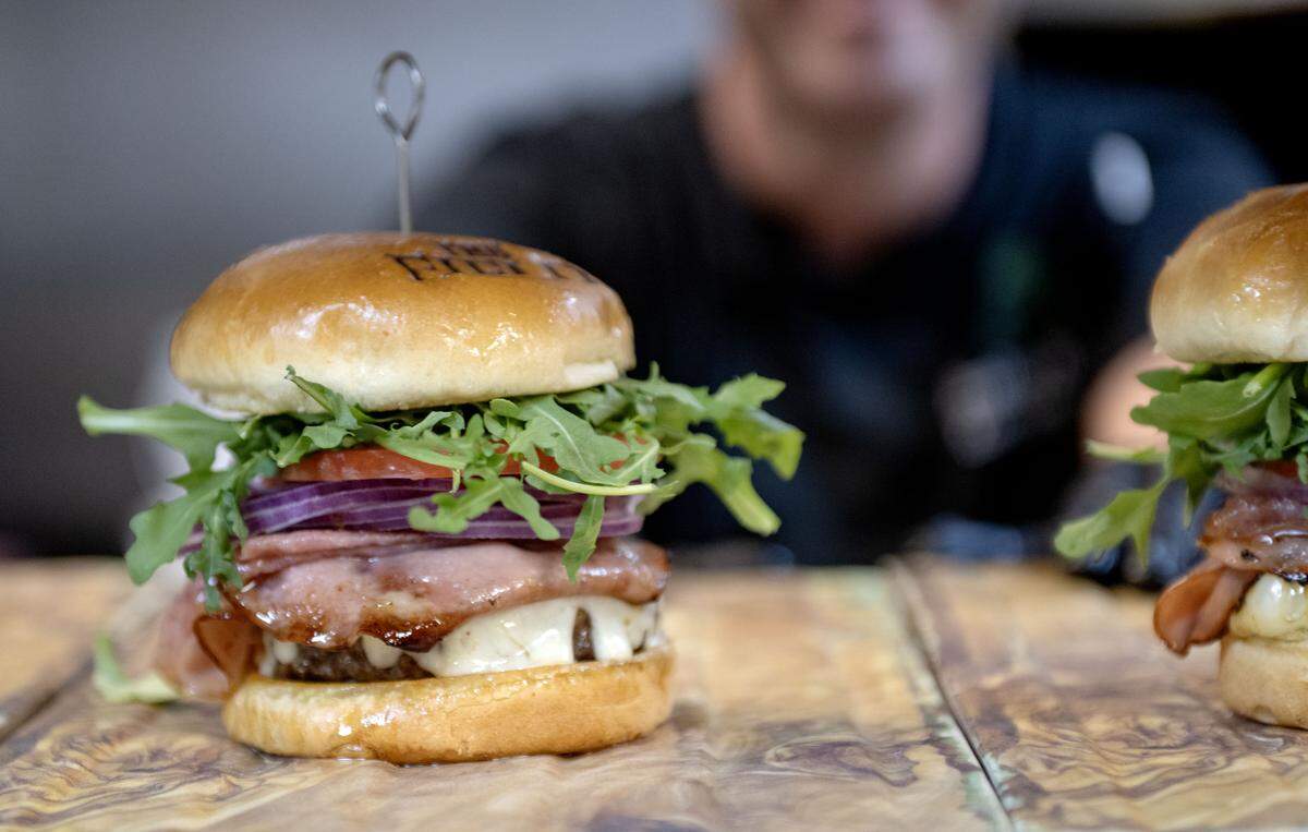 Coach Campbell’s Roman Burger at The Field features salami, mortadella, white cheddar, arugula, tomato, onion, may, Italian dressing on a brioche roll.