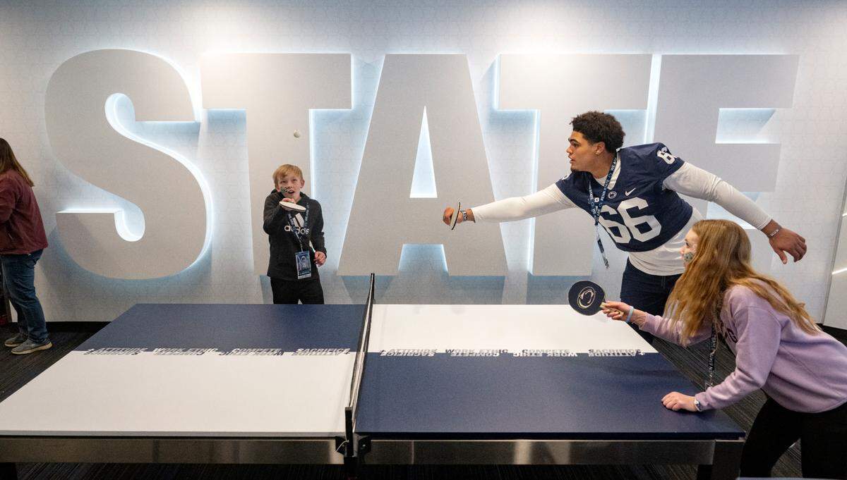 Joel Martin hits the ball as he plays and intense game of ping pong with Audrey Martin, 14, and Penn State offensive lineman Drew Shelton during the Thon Explorers program at the Lasch Building on Saturday, Feb. 18, 2023.